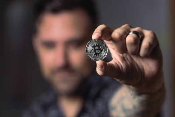 person holding silver bitcoin coin criptomoedas